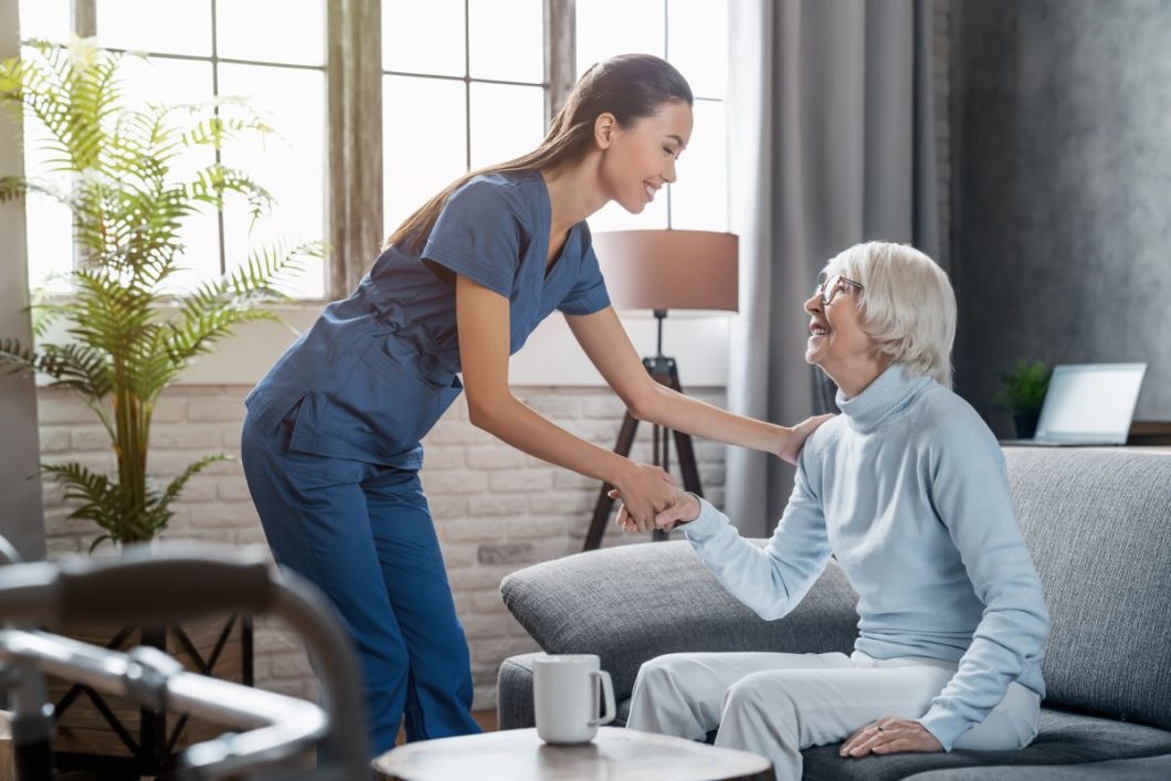 Nurse assists elderly resident in a nursing home lounge